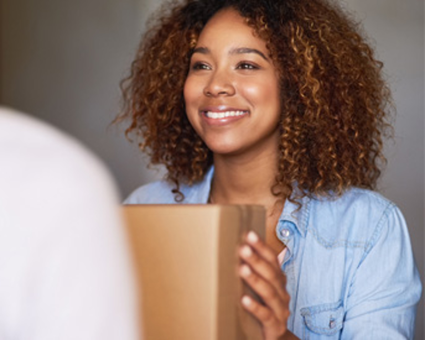 Mujer sonriente recibiendo caja de paqueteria