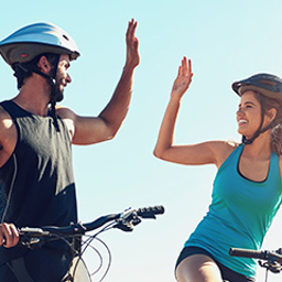 Hombre y mujer en ropa deportiva en bicicleta saludándose 