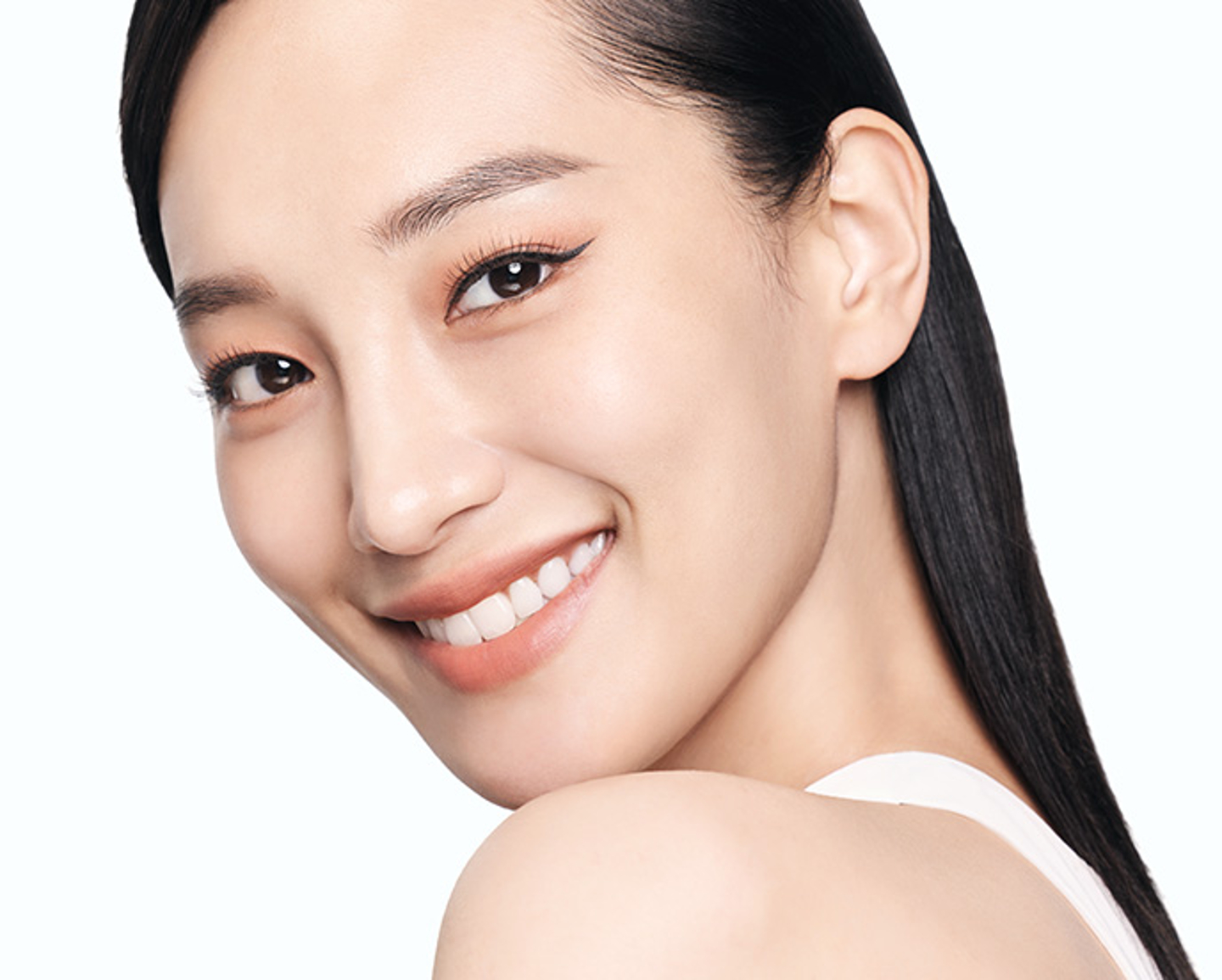 Mujer sonriendo en fondo blanco con beneficios de Artistry Go Vibrant™ Ojos